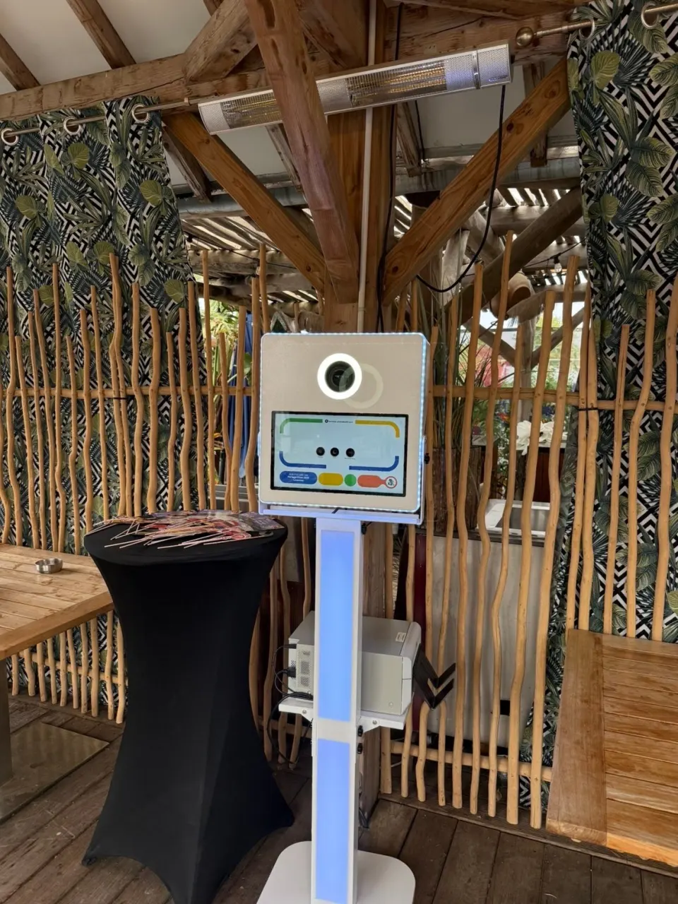 Borne photobooth lumineuse installée sur un lieu de réception, prête avant l'arrivée des invités, l'imprimante sous l'écran