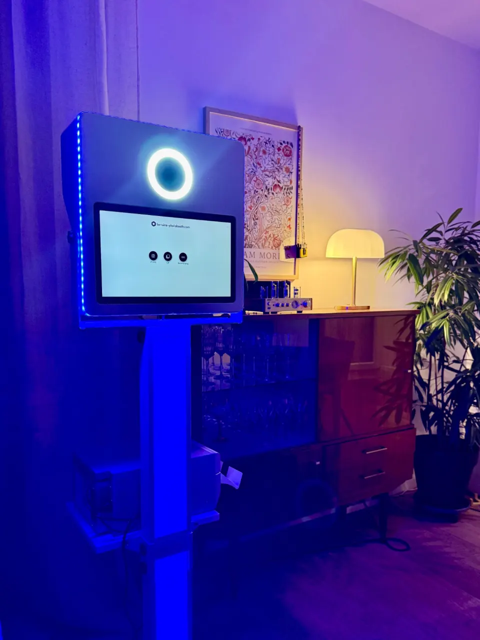 Borne photobooth lumineuse dans un salon, colonne LED violette et anneau lumineux allumé autour de l'objectif