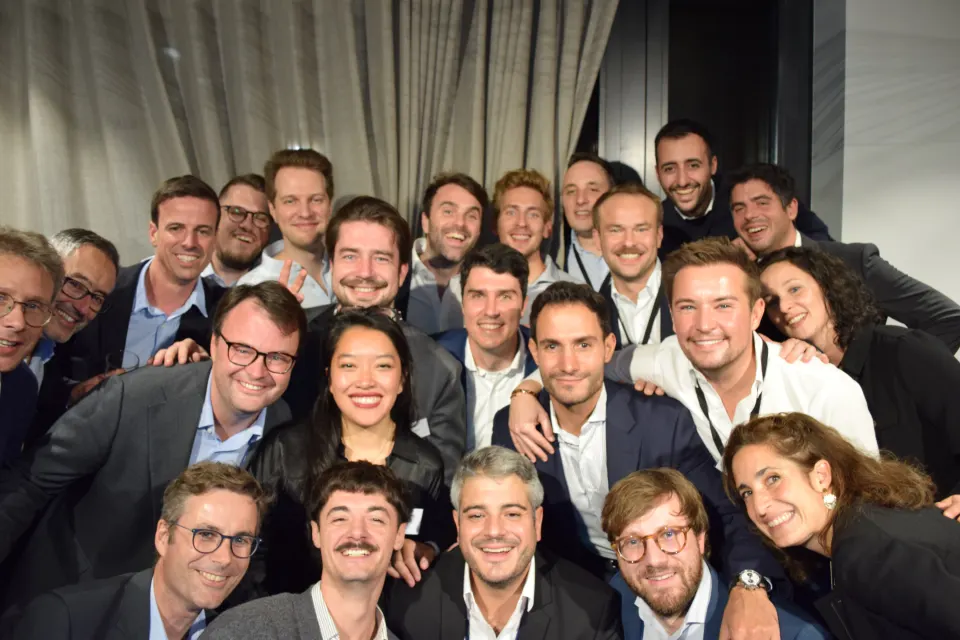 Une vingtaine d'anciens de Deloitte posent ensemble devant la borne, soirée CFA Alumni à Luxembourg