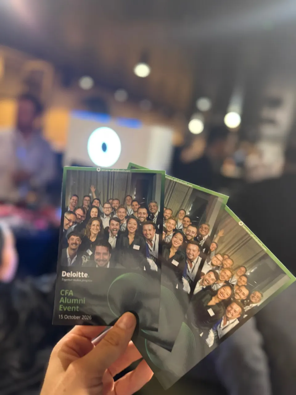 Trois tirages de groupe tenus à la main, au cadre Deloitte « CFA Alumni Event, 15 October 2026 »