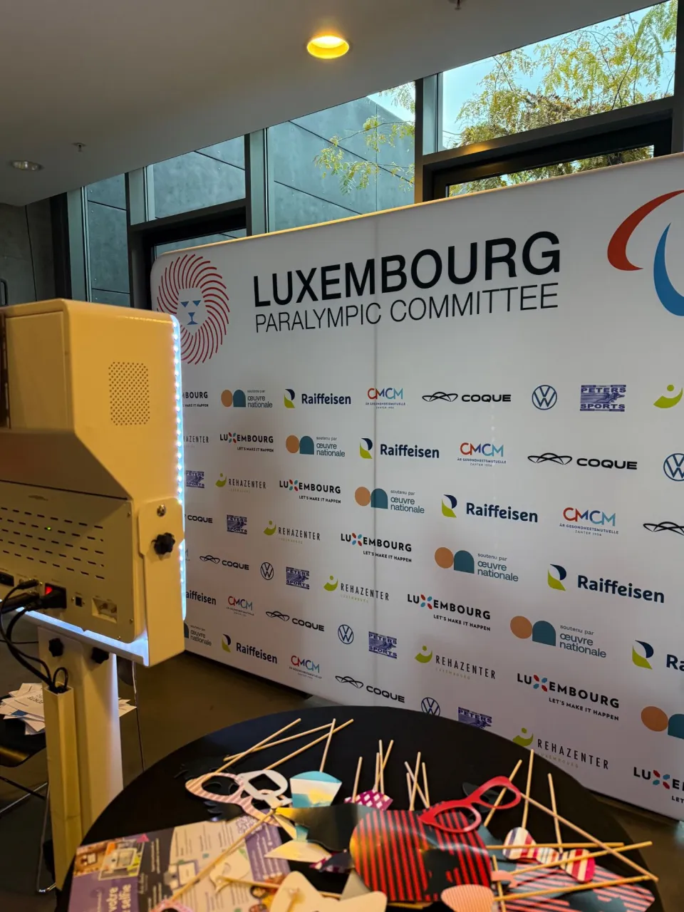 Le mange-debout couvert d'accessoires en carton et de flyers, devant le mur du Luxembourg Paralympic Committee