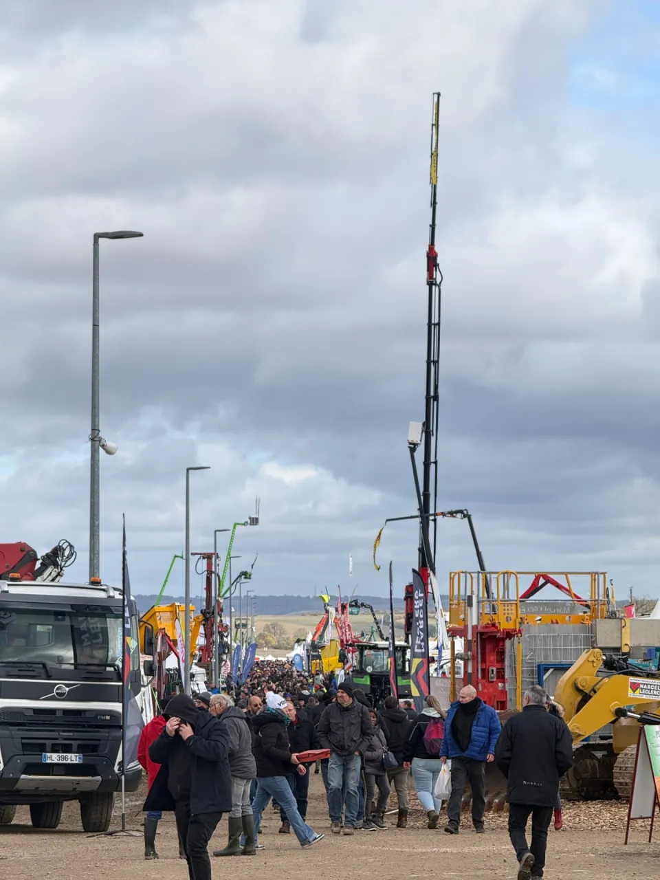 Une allée de la Foire de Poussay pleine de visiteurs, entre camions, grues et engins agricoles