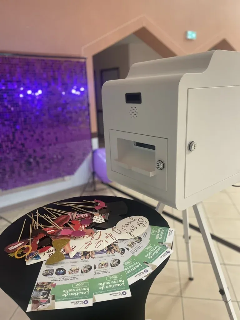 Grande borne devant un mur de sequins violets, flyers sur la table